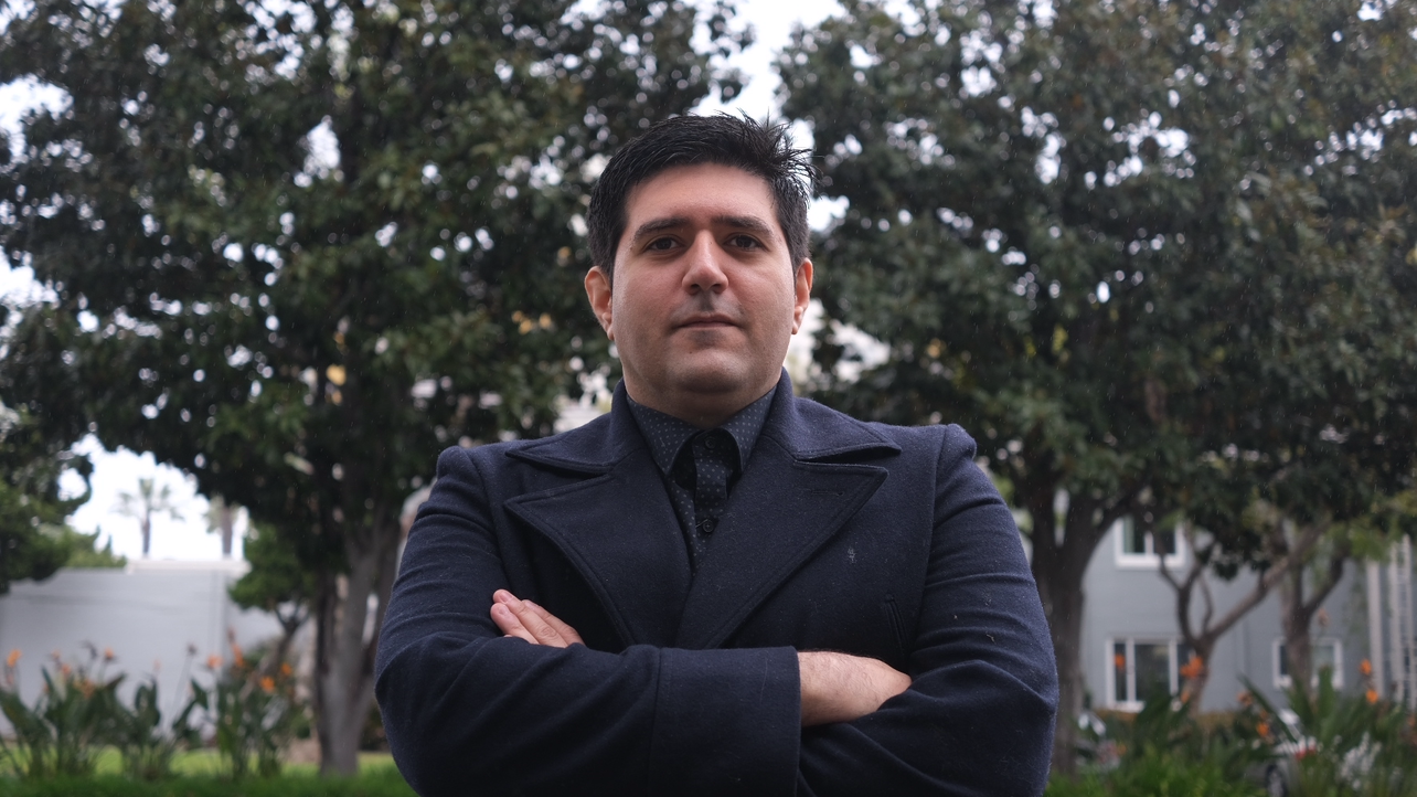 Filmmaker Waheed Naddafi in a black suit, his arms crossed.