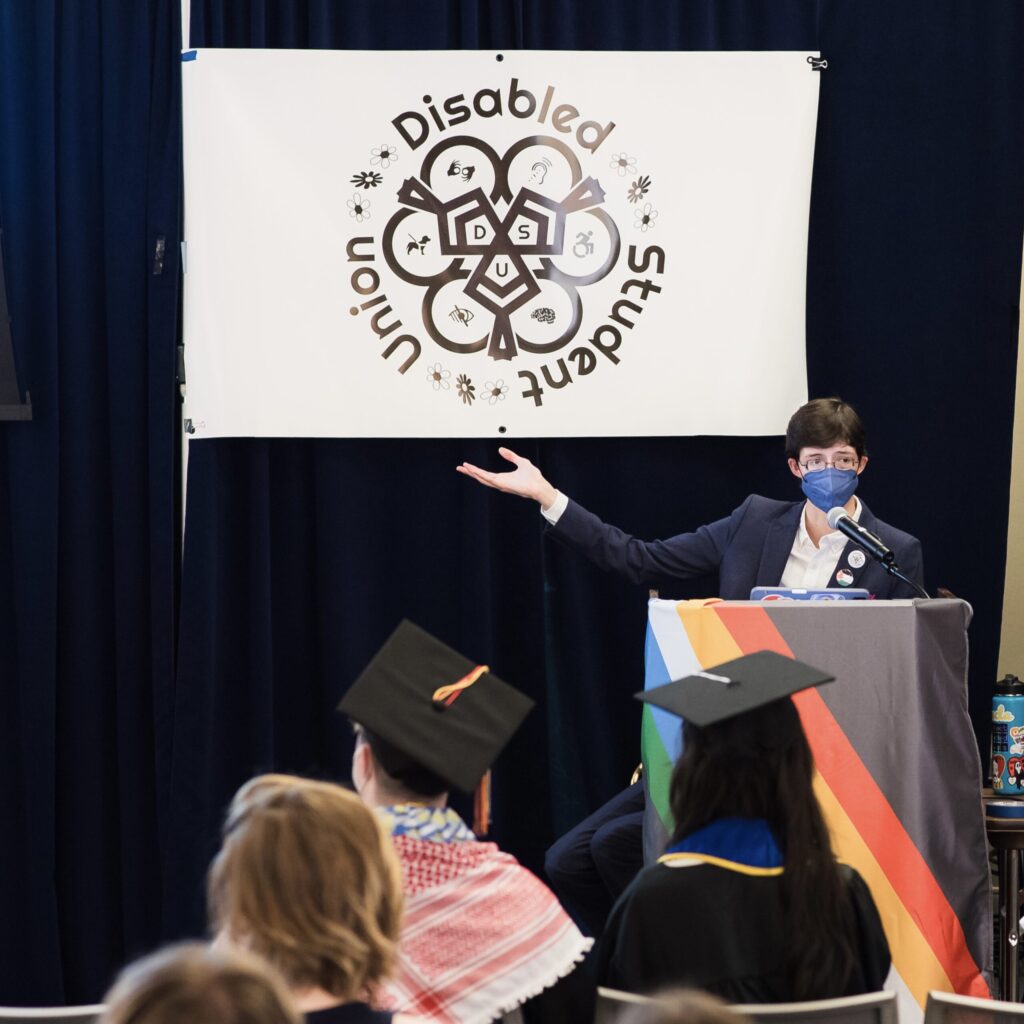 Christopher Ikonomou speaking at the podium at the 2024 Disabled Student Union conference